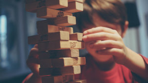 boy-removing-jenga-block-from-jenga-tower