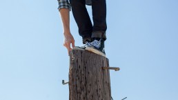 man-standing-precariously-on-top-of-pole