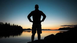 sillhoueted-custom-app-developer-standing-arms-akimbo-looking-heroically-at-lake